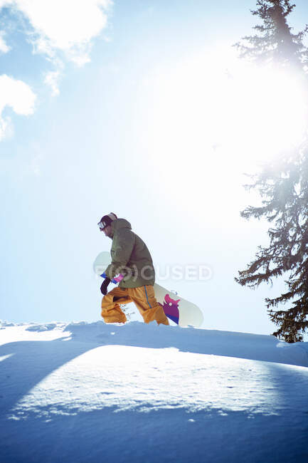 Человек, несущий сноуборд на склоне горы — стоковое фото