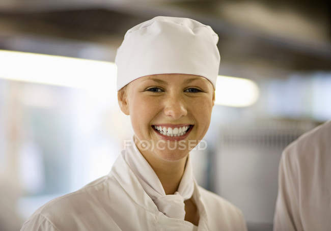 Portrait of female smiling chef in a kitchen — Stock Photo