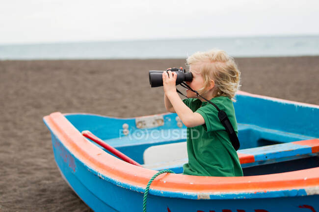 Boy using binoculars on beach — Stock Photo