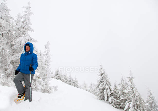 Hombre raquetas de nieve en la ladera nevada - foto de stock