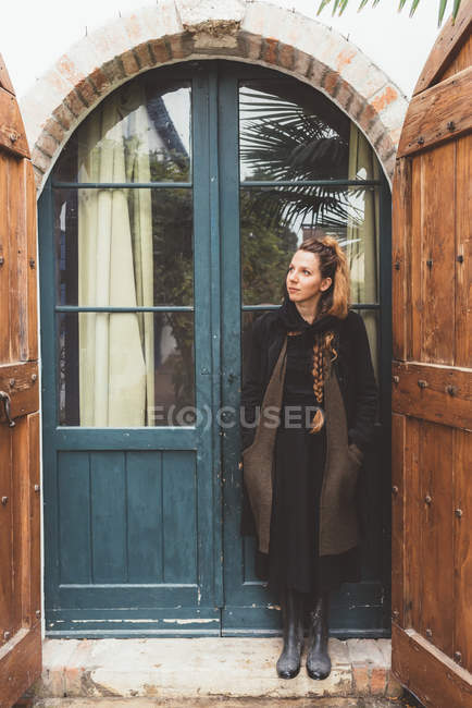 Портрет молодой женщины, смотрящей вверх от двери дома — стоковое фото