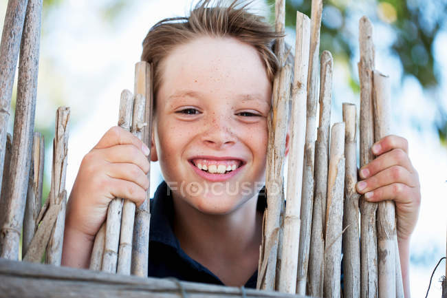 Мальчик улыбается за оградой, фокусируется на переднем плане — стоковое фото