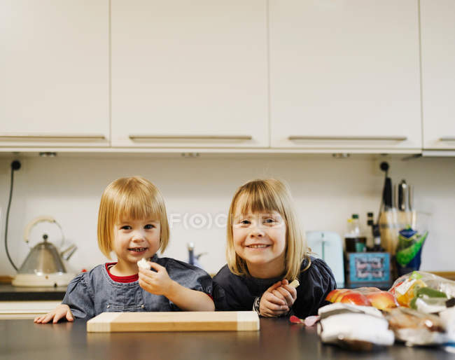 Meninas sorridentes comendo na cozinha — Fotografia de Stock