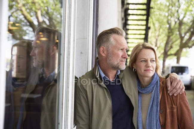 Взрослая пара, обнимающая через окно, Лондон, Великобритания — стоковое фото
