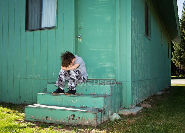 Garçon boudant sur les marches — Photo de stock