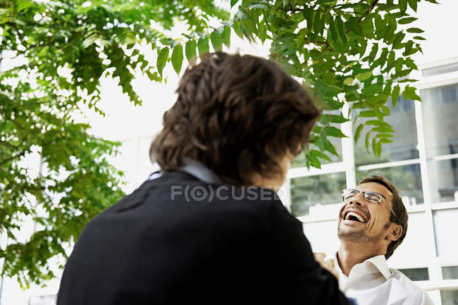 Hombres de negocios riendo en la calle cerca de la oficina - foto de stock