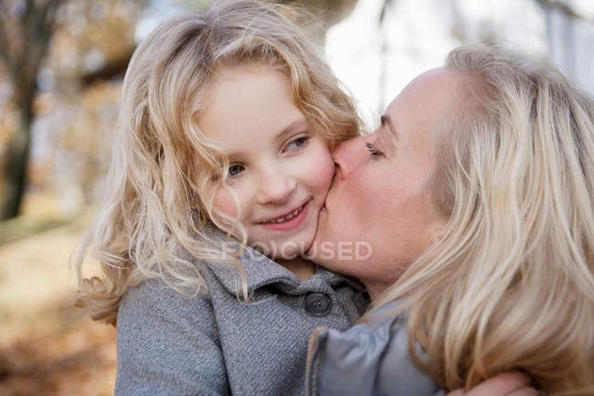 Mother kissing daughter outdoors — Stock Photo