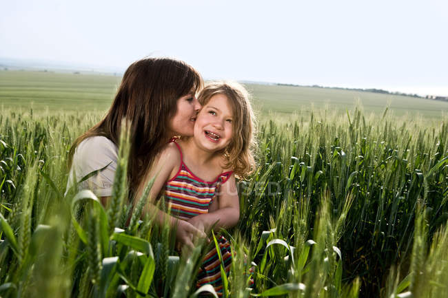 Mãe beijando criança no campo de trigo — Fotografia de Stock