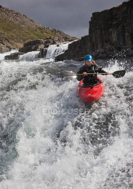 Hombre paseando en canoa sobre cascada rocosa - foto de stock