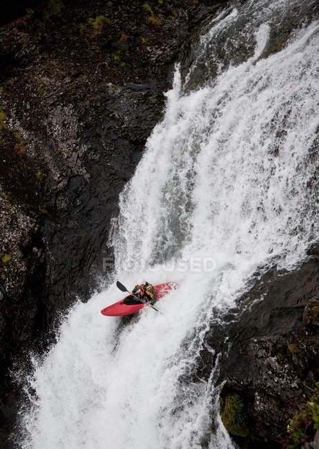 Man canoeing over rocky waterfall — Stock Photo