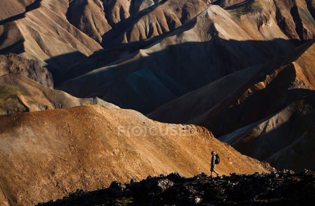 Senderismo del hombre en el paisaje rural rocoso - foto de stock