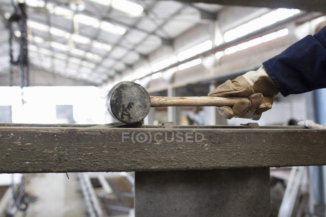 Primer plano del trabajador de fábrica con martillo de goma en fábrica de refuerzo de hormigón - foto de stock