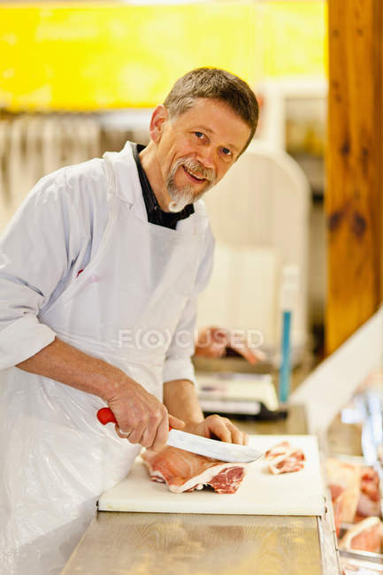 Carniceiro cortando carne no balcão — Fotografia de Stock