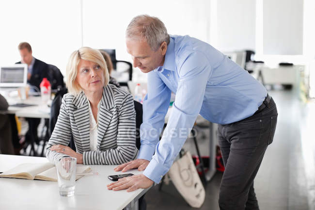 Businessman standing near woman at table — Stock Photo