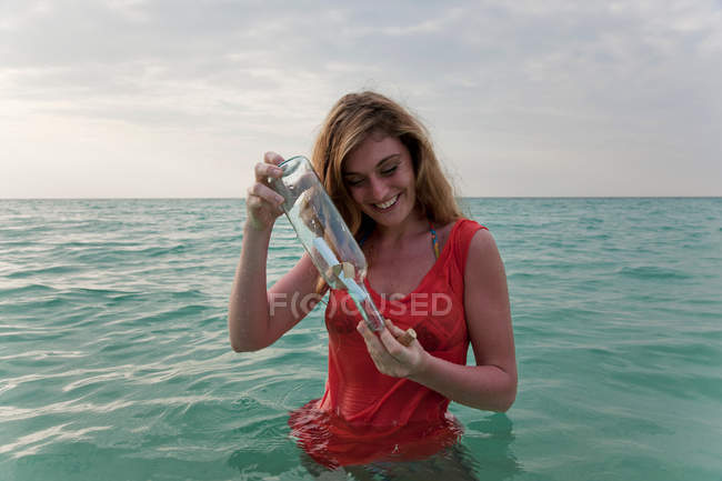 Mujer en el mar con mensaje en una botella - foto de stock