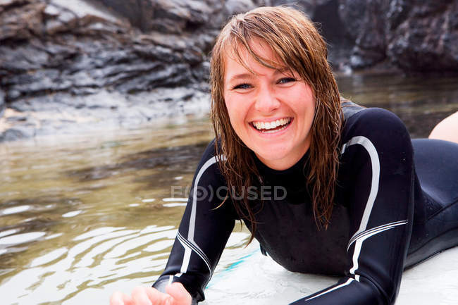 Donna sdraiata sulla tavola da surf in acqua — Foto stock