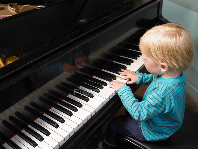 Маленький мальчик играет на пианино — стоковое фото