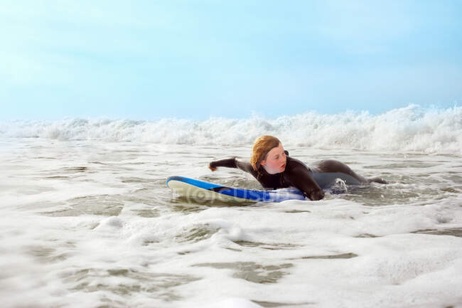 Weibchen liegt auf Surfbrett und paddelt — Stockfoto