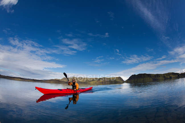 Hombre remando canoa en un lago tranquilo - foto de stock