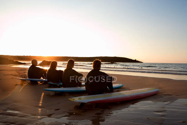 Чотири людини сидять на пляжі — стокове фото