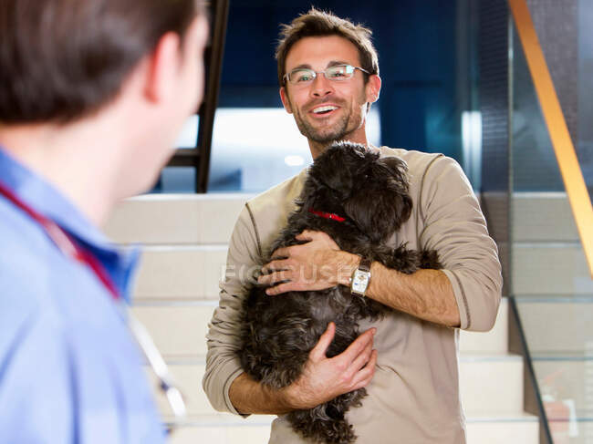 Человек держит собаку у ветеринара — стоковое фото