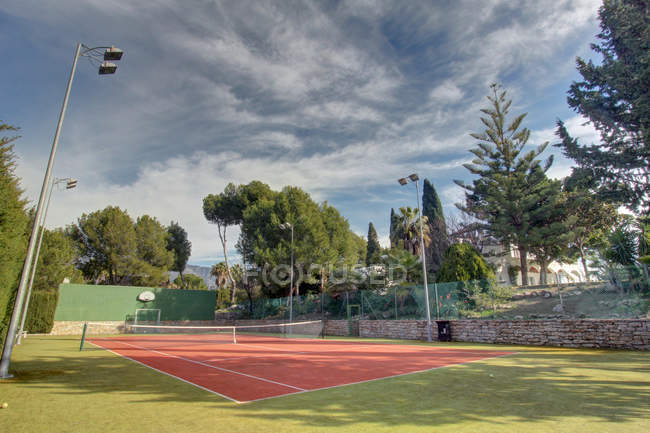 Court de tennis vide entouré d'arbres — Photo de stock