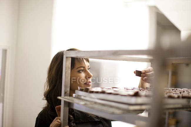 Femme inspectant le chocolat dans la cuisine commerciale — Photo de stock