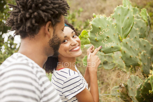 Пара, указывающая на имена на листьях кактусов, пляж Ипанема, Рио-де-Жанейро, Бразилия — стоковое фото