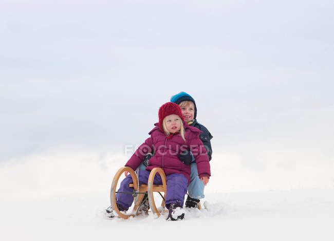 Kinder sitzen auf Schlitten im Schnee — Stockfoto