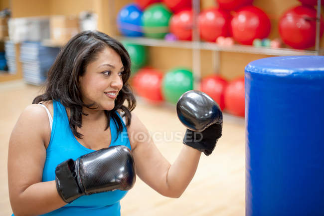 Жінка ударяє сумку в спортзалі — стокове фото