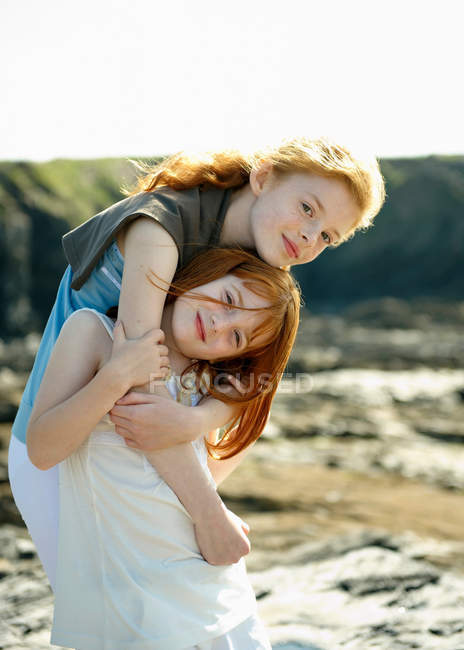 Chica abrazando a su hermana pequeña - foto de stock