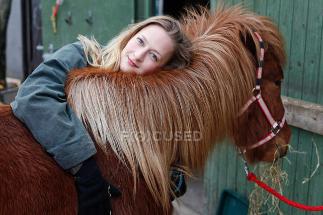 Улыбающаяся женщина обнимает лошадь на улице — стоковое фото