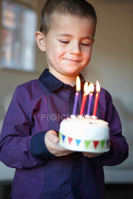Хлопчик тримає мініатюрний торт зі свічками — стокове фото