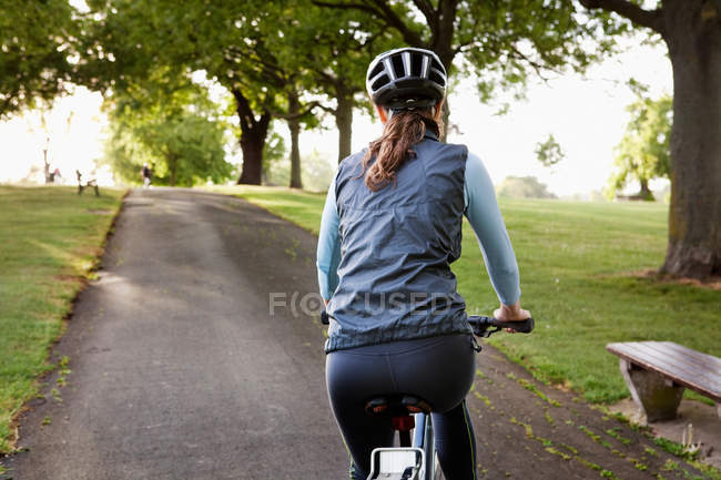 Donna in bicicletta in salita al parco — Foto stock