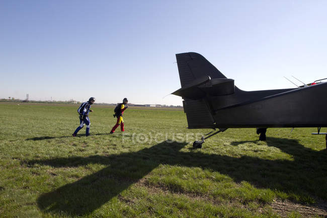 Skydivers walking towards airplane — Stock Photo