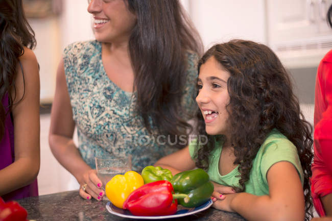 Chica sonriente con la familia en la cocina - foto de stock