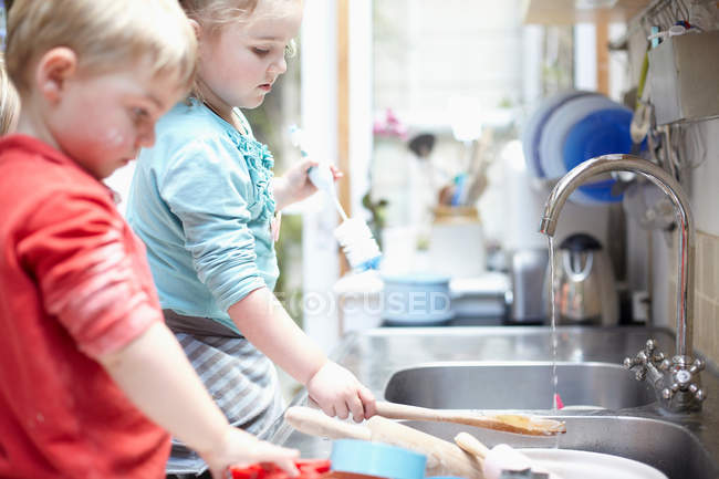 Children washing dishes together — Stock Photo