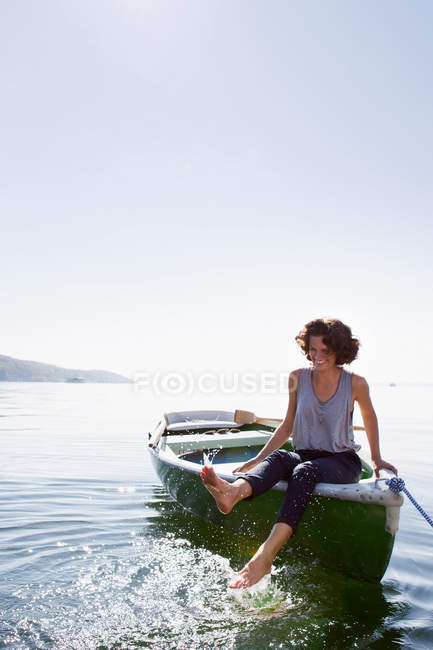 Femme balançant pieds du bateau dans le lac — Photo de stock