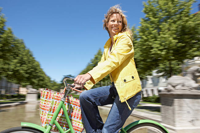 Woman bicycling with shopping bag — Stock Photo