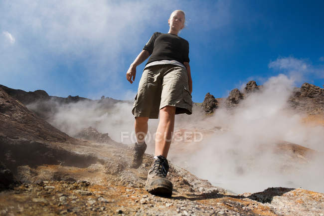 Donna escursionismo vicino geyser, vista angolo basso — Foto stock