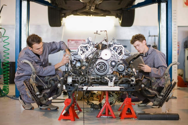 Механики, работающие над автомобильным двигателем — стоковое фото