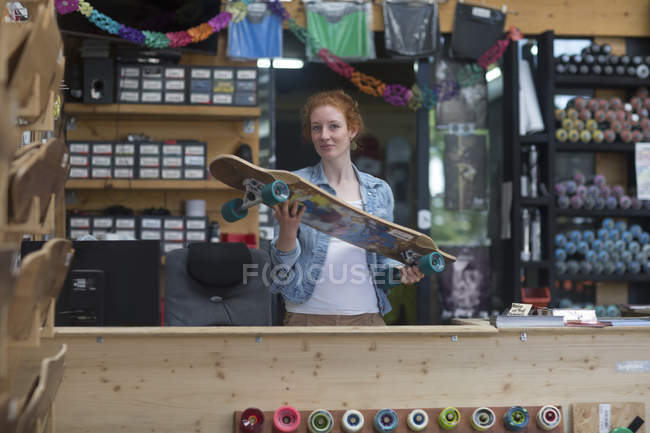 Femme vendeur tenant skateboard — Photo de stock