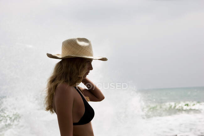 Ragazza con cappello di paglia, spruzzi d'acqua dietro di lei — Foto stock