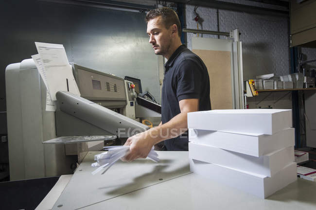 Arbeiter entsorgt Papierschnipsel in Druckerei — Stockfoto