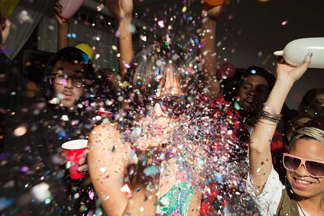 Люди танцюють на вечірці, жінка дме блиск — стокове фото