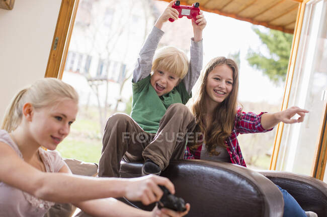Teenage girls and boy playing games console — Stock Photo