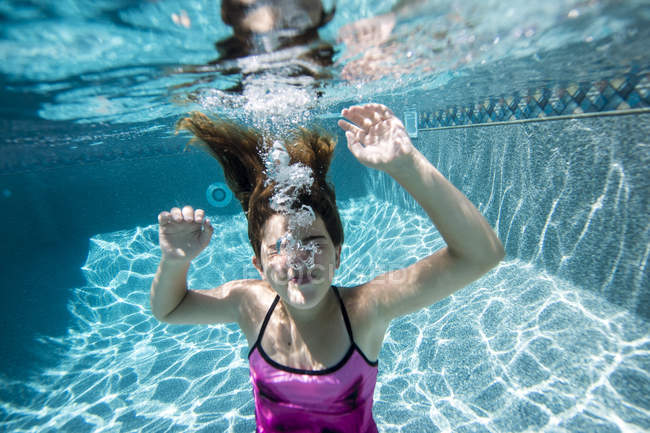 Chica soplando burbujas en la piscina - foto de stock