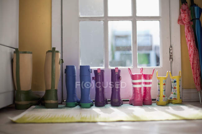 Tidy row of rubber boots at back door — Stock Photo