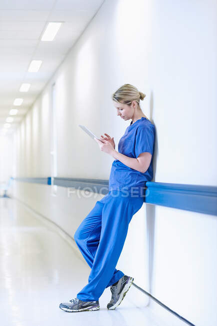 Arzt steht auf Flur und schaut auf digitales Tablet — Stockfoto