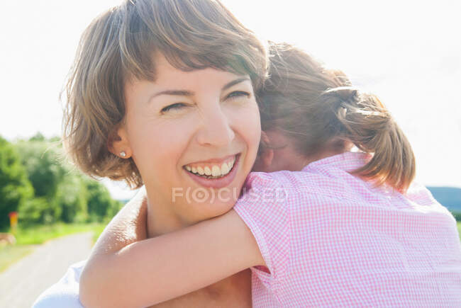 Mãe segurando filha, sorrindo — Fotografia de Stock